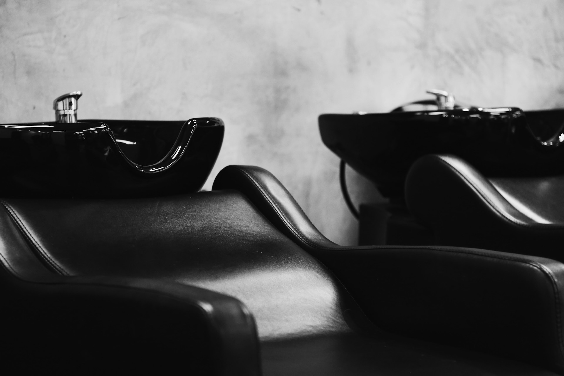 Black and white picture of two empty salon wash station chairs.