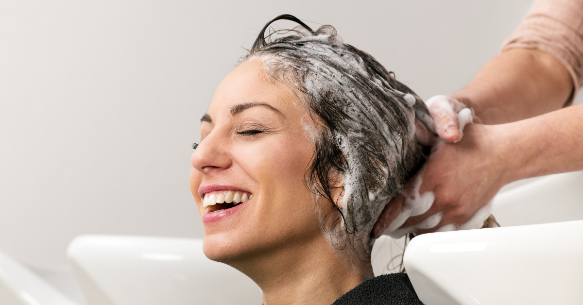 Salon Client Laughing While Her Hair is Being Shampooed at the Shampoo Bowl